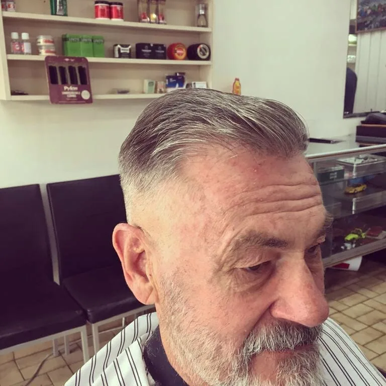 Older man with grey slicked-back cut and trimmed beard