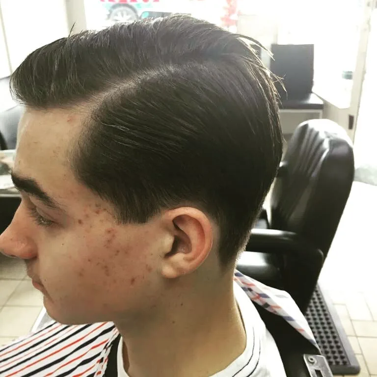Young man in the barber chair: side profile, slicked longer top with clean taper
