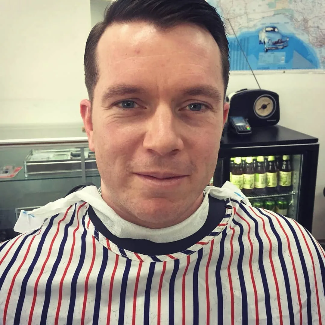 Man with short back-and-sides, shop interior behind